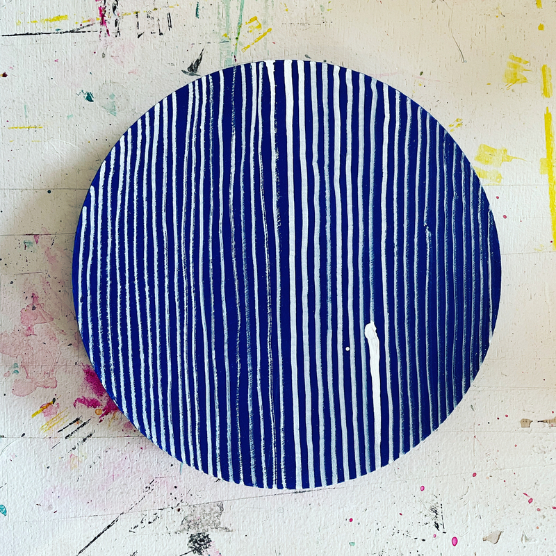 round drawing with indigo blue background and hand drawn vertical white ink lines